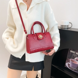 Sac à main vintage rouge foncé avec texture crocodile et fermoir floral porté par un mannequin