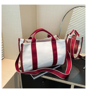 Detail of white canvas tote bag with burgundy straps and leather trim in natural light