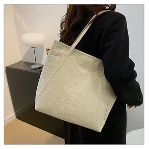 Detail of cream white tote bag featuring premium crocodile texture and long shoulder straps
