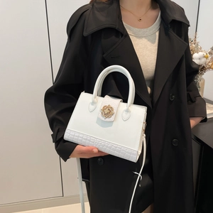 Sac bandoulière blanc avec motif crocodile et boucle fleurie dorée sur manteau noir