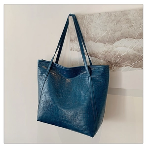Detail shot of navy blue crocodile pattern tote bag with embossed texture and twin handles