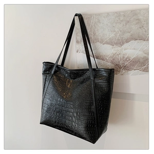 Detail shot of black crocodile embossed tote bag texture with long shoulder straps