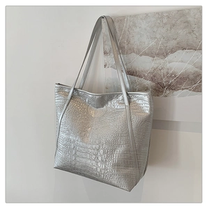 Detail of silver tote bag with crocodile texture and leather shoulder straps