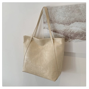 Close-up of off-white tote bag featuring elegant crocodile texture and dual shoulder straps