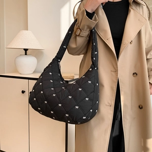 Schwarze Stepptasche mit weißen Schleifen an einem Modell im Trenchcoat-Look