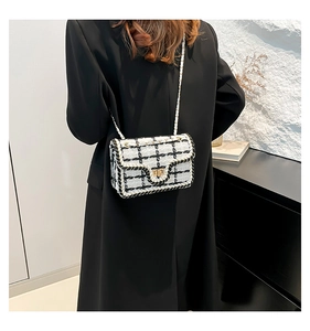 Detail van de zwart-witte tweed crossbodytas met een gouden metalen draaisluiting
