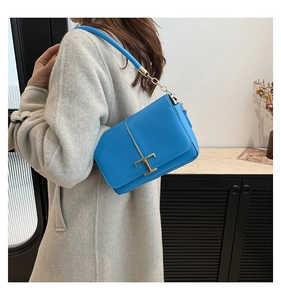 Détail du sac bandoulière en cuir bleu vif avec une boucle en métal doré en forme de T