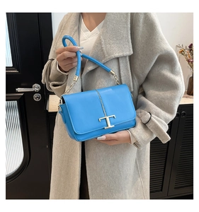 Détail du sac à bandoulière en cuir bleu vif avec fermoir en T doré et bandoulière chaîne