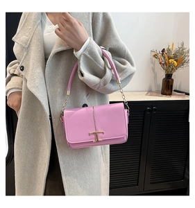 Détail du sac à main rose en cuir lisse avec boucle en T dorée et anse en chaîne métallique