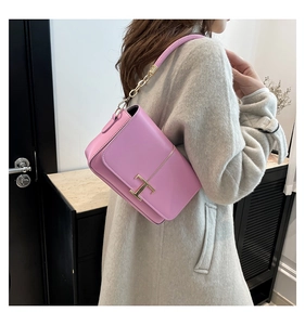 Détail du sac en cuir rose avec boucle métallique en T dorée et bandoulière en chaîne