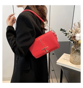 Détail d'un sac bandoulière en cuir rouge avec fermoir doré en T et bandoulière