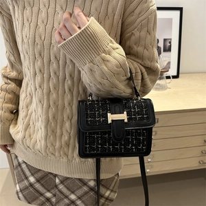 Chic black leather and tweed square handbag with a gold H-clasp in a lifestyle setting