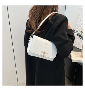 Détail du sac à bandoulière en cuir blanc avec fermoir en T doré et bandoulière chaîne