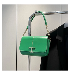Détail du sac à rabat en cuir vert avec fermoir en T doré et bandoulière chaîne