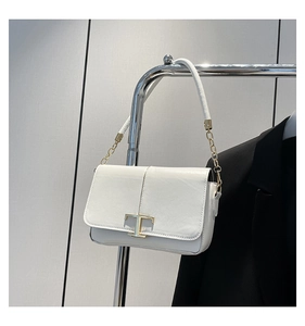 Gros plan du sac demi-lune en cuir blanc avec boucle métallique dorée en forme de T