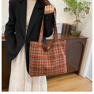 Close-up of vintage plaid tote bag featuring red and blue woven fabric with long handles