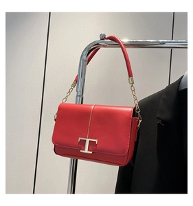 Gros plan du sac bandoulière en cuir rouge avec boucle métallique dorée en forme de T