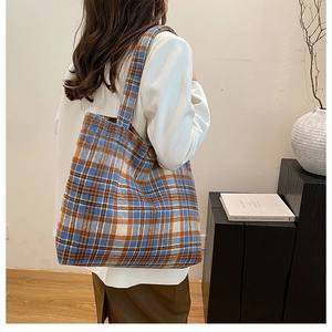 Close-up of winter plaid tote bag with wooden button on a model in white blazer