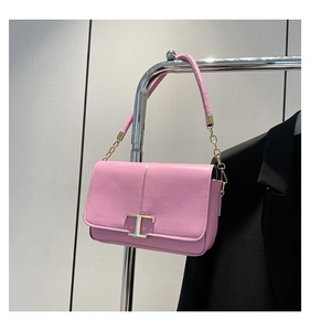 Détail du sac bandoulière en cuir rose avec fermoir T doré et élégante chaîne en métal