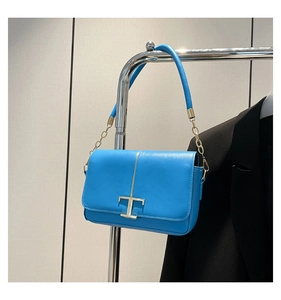 Détail d'un sac en cuir bleu vif avec un fermoir en métal doré en forme de T élégant