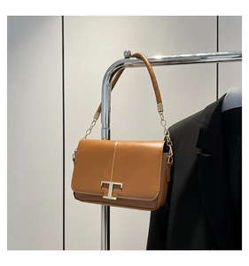 Détail d'un sac bandoulière en cuir marron avec fermoir T doré et bandoulière chaîne