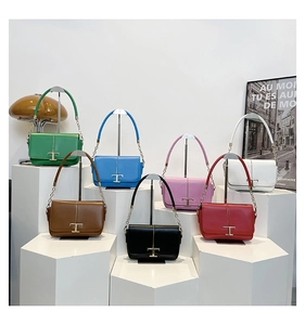 Série de sacs bandoulière colorés avec fermoirs en T dorés sur des socles blancs