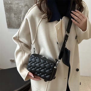 Chic black quilted crossbody bag with wide strap and pouch on a beige coat outfit