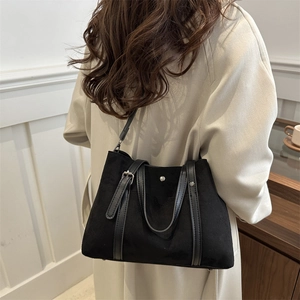 Minimalist large black tote bag with shoulder strap shown in a modern interior setting