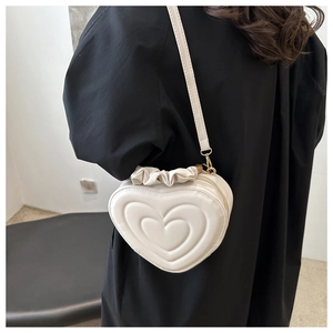 Chic heart-shaped crossbody bag in creamy white with quilted pattern and ruffled trim