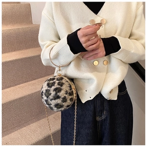 Chic leopard print sphere handbag with gold ring handle and chain strap on a model