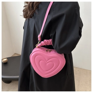 Detailed side view of a pink heart-shaped bag with pleated handle on a black dress