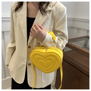 Détails d'un sac à main jaune en forme de cœur avec texture matelassée et détails dorés