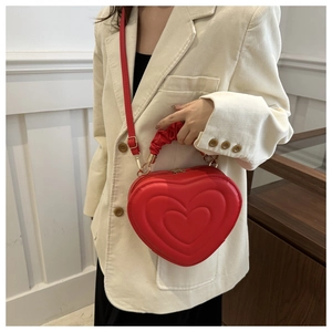Detail of red heart-shaped bag featuring quilted leather and gold-tone metal hardware