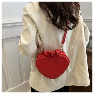 Détail du sac bandoulière rouge en forme de cœur avec texture matelassée et volants