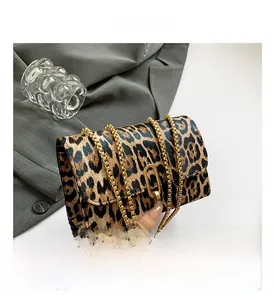 Detail of leopard print handbag featuring a gold oval clasp and elegant metal chain strap