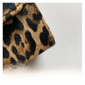 Macro detail of cross-grain leather texture with leopard print and precise stitching