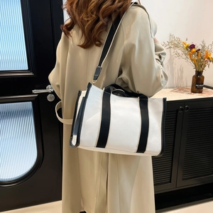 Minimalist canvas tote bag with black strap details and adjustable shoulder strap
