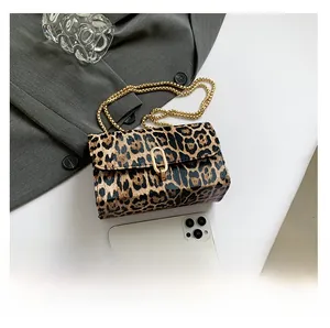 Detail view of leopard print crossbody bag with gold chain strap and metal buckle closure