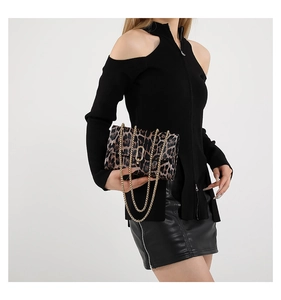Detail of leopard print leather crossbody bag with gold chain strap on model outfit