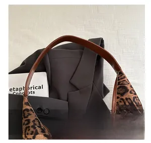 Detail of leopard print tote bag with brown leather handles and smooth stitching