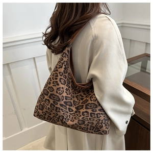 Detail of leopard print tote bag with brown leather straps worn on a beige coat