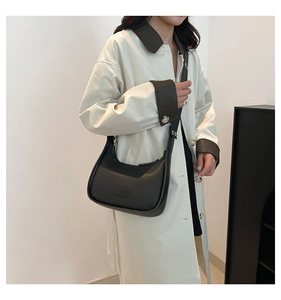 Model wearing a black crescent hobo bag made of smooth matte leather with adjustable strap