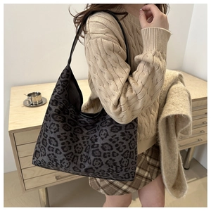 Detail der Leoparden-Einkaufstasche mit Lederriemen an einem Modell mit Strickpullover