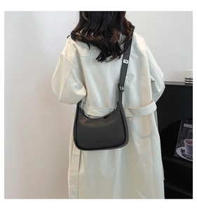 Close-up of black crescent moon shoulder bag featuring matte leather texture and silver buckle