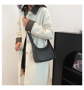 Close-up of black crescent shoulder bag with Fashion Bag EST 1995 lettering details