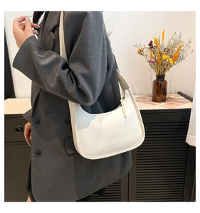 Close-up of a white crescent shoulder bag with black lettering and minimalist design