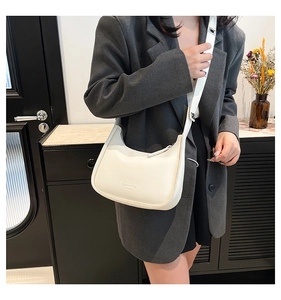 Model wearing a minimalist cream half-moon crossbody bag with Fashion Bag typography