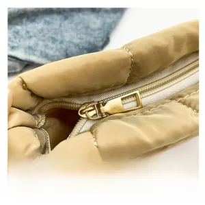Close-up van de gouden metalen rits en gewatteerde nylon stof van de beige tas