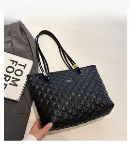 Macro shot of black quilted faux leather tote bag with gold hardware and rhombic stitching