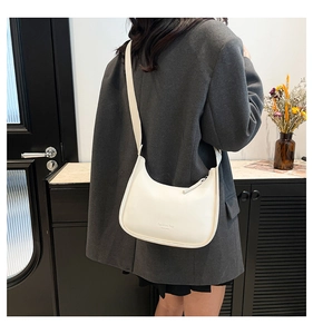 Detail of a creamy white crescent bag showing the embossed logo and smooth leather texture